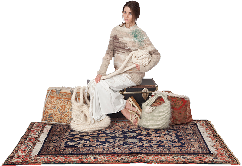 Anne Guitteau seated with sculptural knitwear accessories and textile pieces