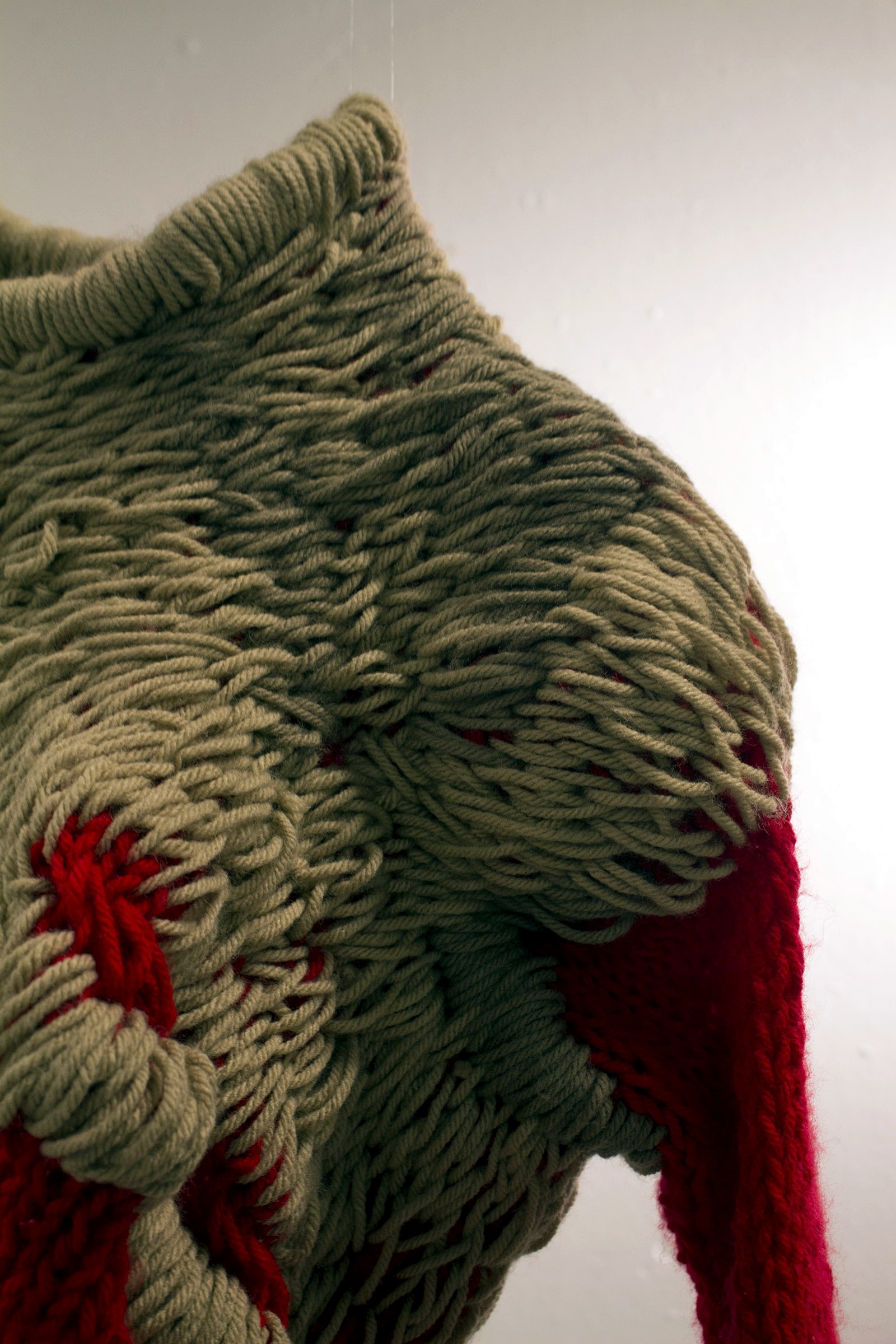 Close crop of overscale looped knit construction in red and taupe yarn